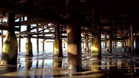 Ocean-Waves-hitting-the-legs-of-the-Crystal-Beach-Pier,-San-Diego,-California