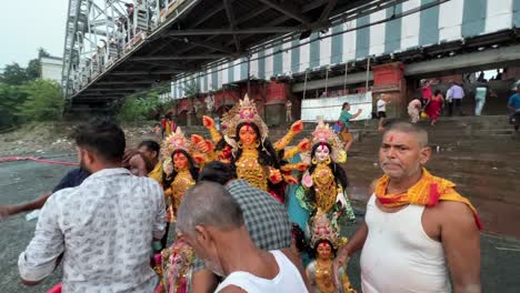 goddess durga idol getting ready to be immersed into holy ganga river under howrah bridge in kolkata, india.