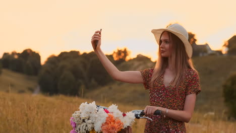 Summer-young-beautiful-girl-standing-with-Bicycle-photographed-taking-selfie-on-her-mobile-phone.