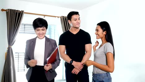 una pareja joven que busca comprar o alquilar una nueva casa. un agente inmobiliario profesional presenta una casa moderna al cliente. resolución 4k.