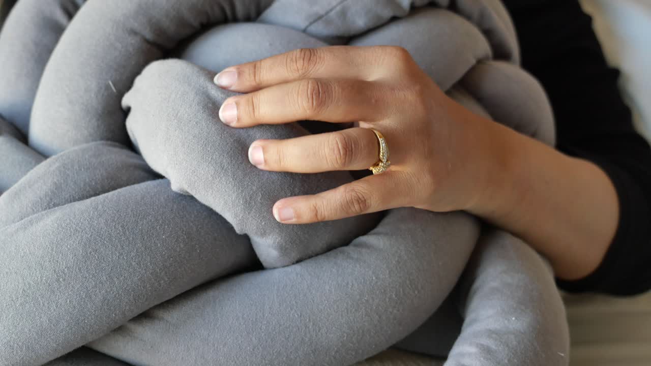 회색 매 된 베개 를 들고 있는 여자 의 손