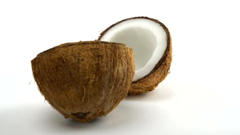 ripe tropical coconut split in two halves rotating on a white background. exotic fruits, loopabe