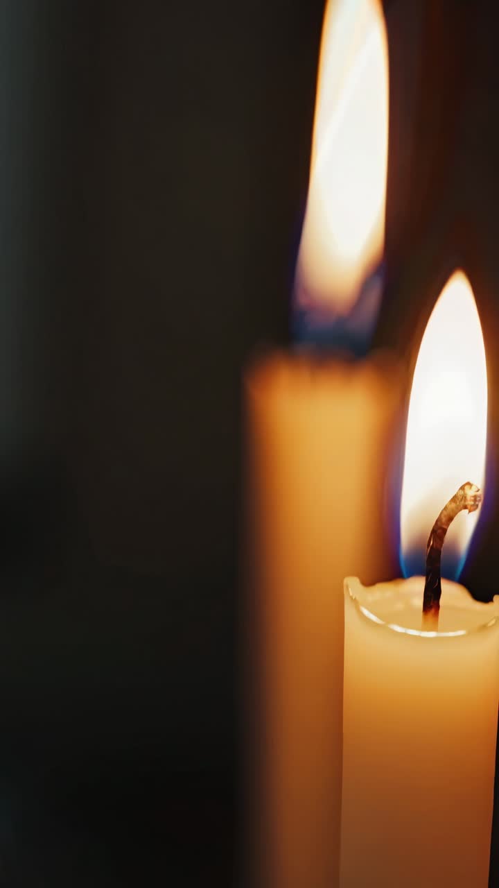 Video ravvicinato di due candele accese con una messa a fuoco morbida. L'angolo della telecamera è leggermente elevato.