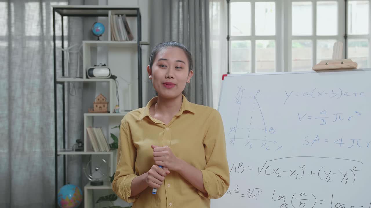 自宅でマーカーペンを使って数学を教えるアジア人女性教師。