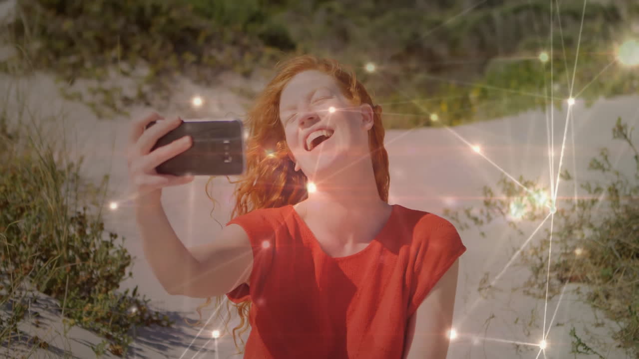 On beach, woman taking selfie with glowing light effects like animation