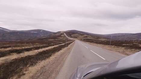 adventurous drive along the roads of the scottish highlands, with camera capturing the front of the car as it drives through brown barren landscapes of the highlands as the landscapes pass by