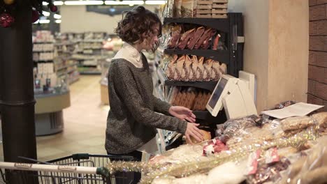 a girl weighs pomelo on an electronic scales in a supermarket and puts a sticker with a price. pomelo in a grid package. side view. slow motion