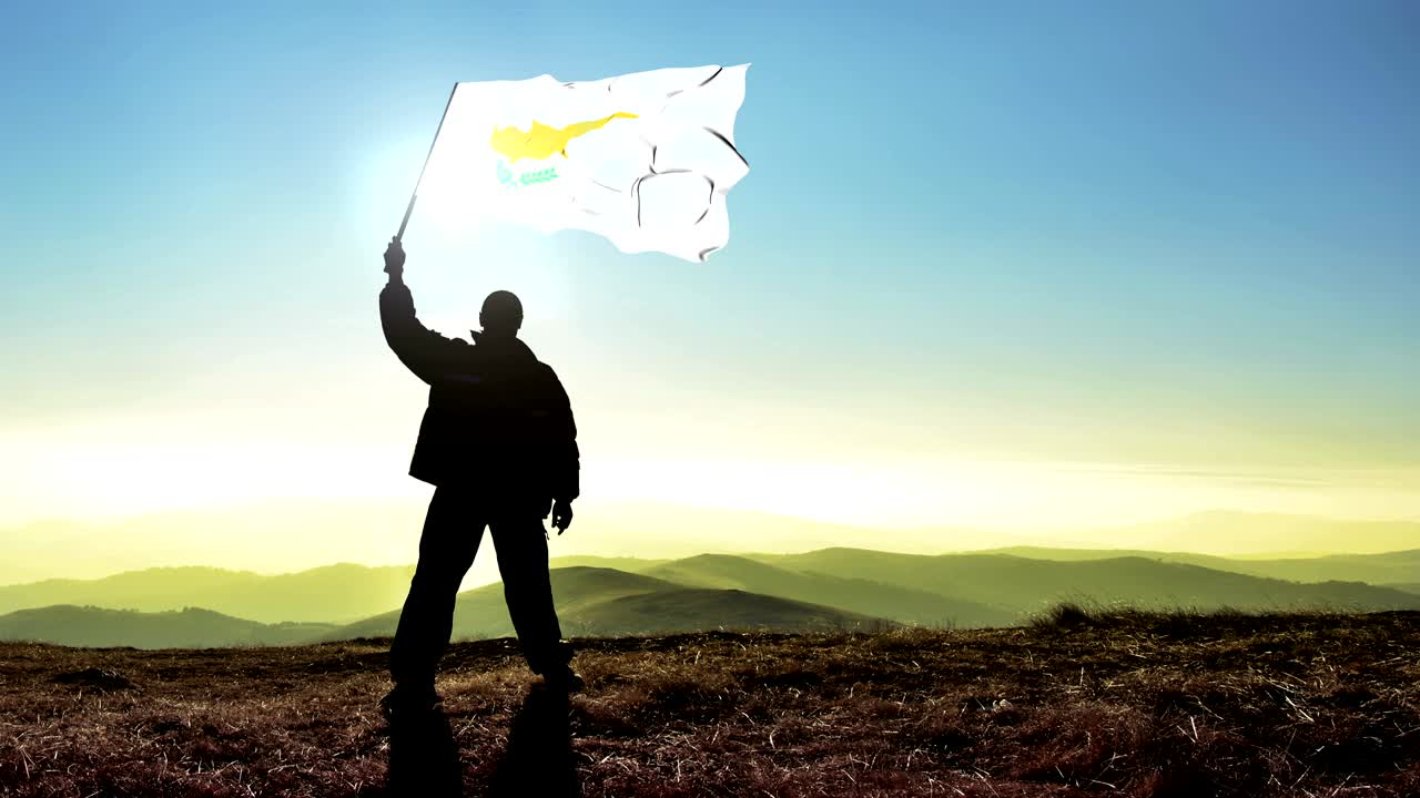 hombre silueta exitoso ganador agitando la bandera de chipre en la parte superior del pico de la montaña. fondo de bucle cinemagraph