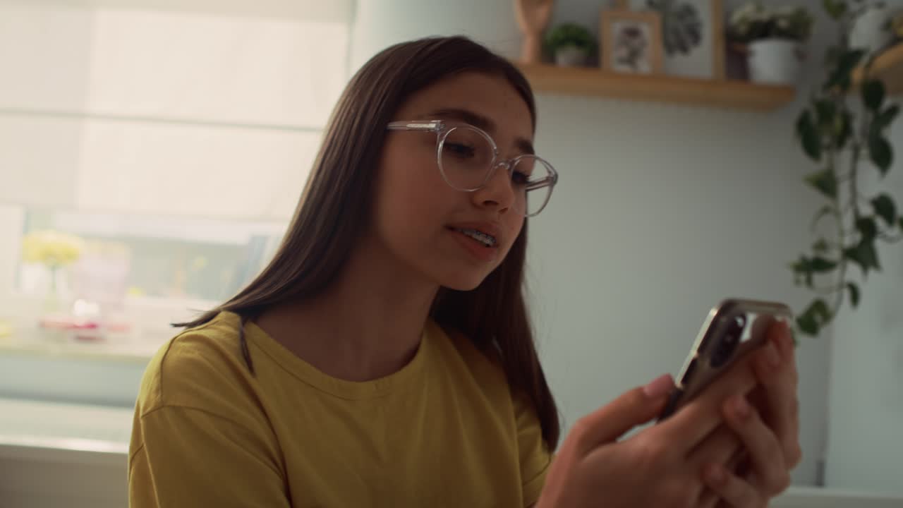 adolescente caucásica haciendo una videollamada mientras está sentada y al lado en su cama