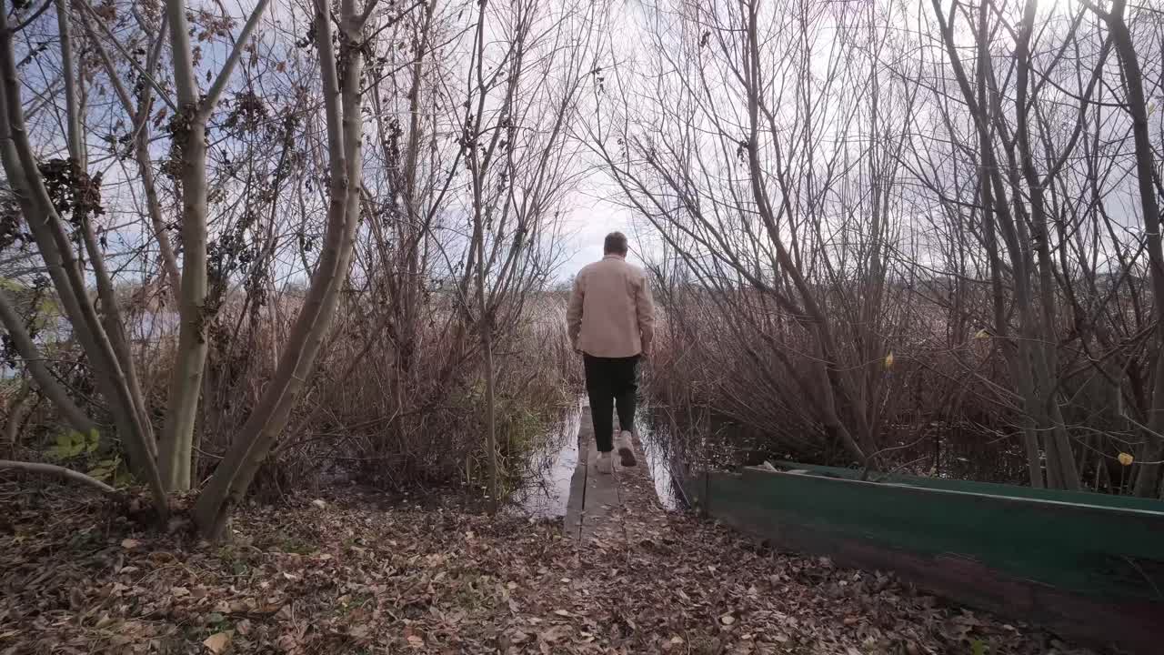 Man walks on wooden pier in a autumn day