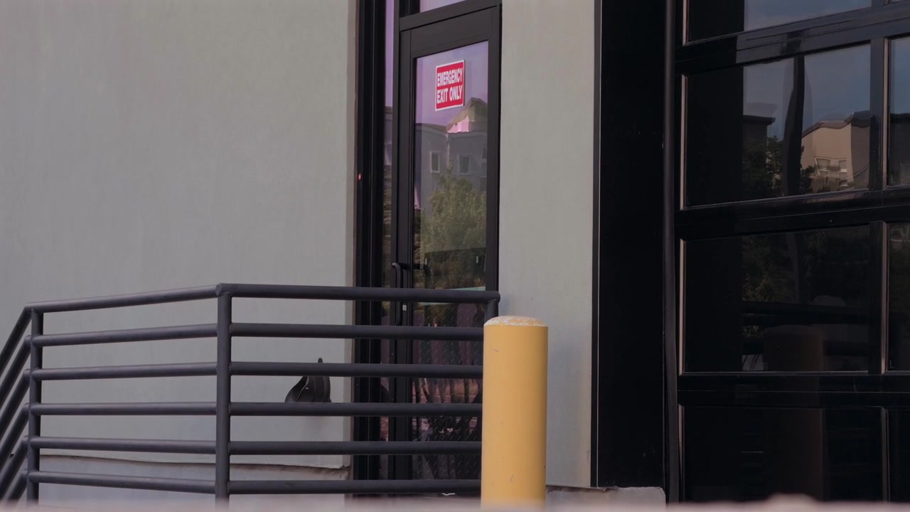 Un movimento ascendente rivela una porta di uscita esterna e finestre riflettenti.
