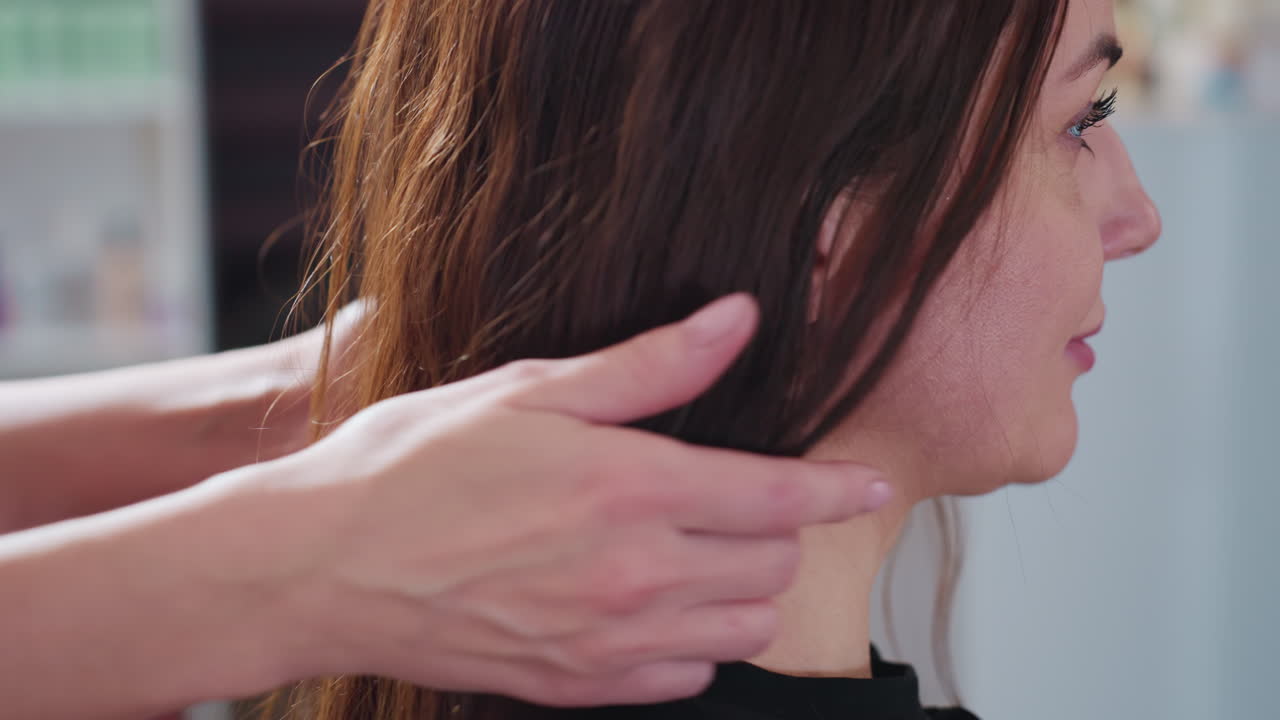 세련된 여성이 준비하고 있어요. 차분한 프로가 미용실에서 머리 모양을 다듬고, 침착한 여성이 밝은 선반을 배경으로 스타일링을 위해 머리를 조심스럽게 준비하고 있어요.