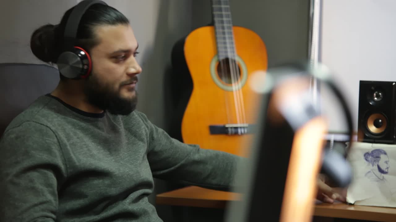 joven con auriculares inalámbricos relajándose escuchando música sentado en el estudio, chico feliz y relajado disfrutando del sonido del salón con fondo de guitarra en un estado de ánimo tranquilo