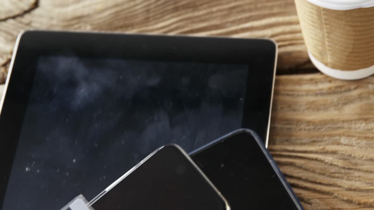 taza de café desechable, tableta digital, teléfono móvil, tarjeta de crédito en una tabla de madera