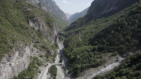 Frontales-Drohnenvideo,-Das-Sich-Zwischen-Den-Hügeln-Des-Valbone-Tals-Und-über-Der-Straße-Azem-Hajdariy-Und-Dem-Fluss-Bewegt