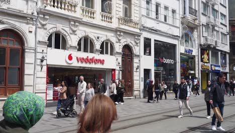 people walking on a busy city street with stores and shops