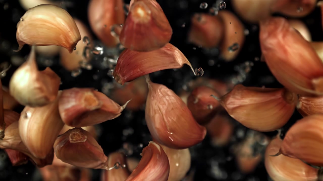 Fresh Garlic Cloves Falling with Water Drops in Slow Motion