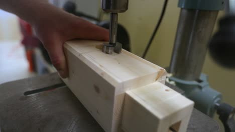 taladrar una ranura de espiga en una viga de madera en una taladradora en cámara lenta mientras las astillas de madera se desplazan en todas las direcciones