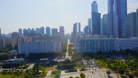 Drone-shot-traveling-forward-above-a-park-toward-the-a-residential-area-and-business-buildings-in-Seoul-city-during-a-sunny-day