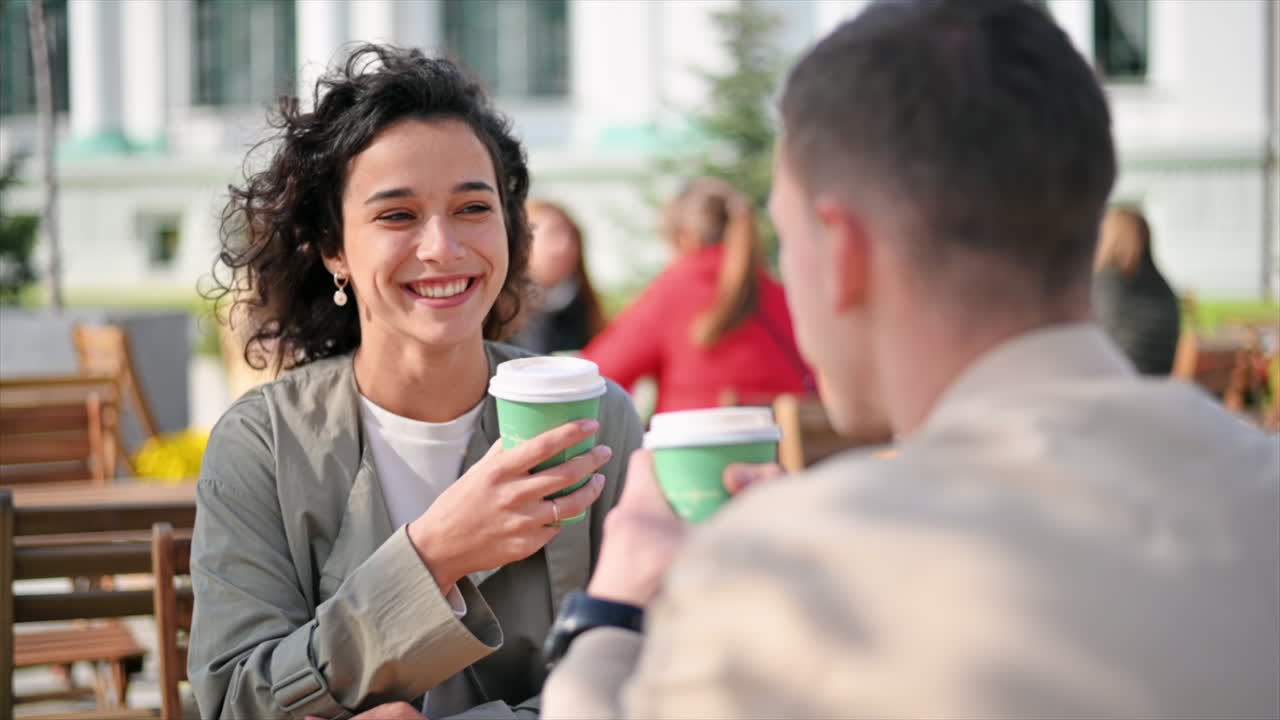 A happy couple outdoors near a cafe. Looking at each other, smiling and talking, coffee. Autumn atmosphere. Slow motion