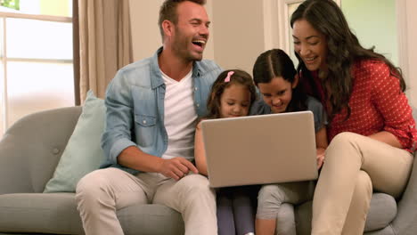 Familia-Feliz-Usando-Una-Computadora-Portátil-En-El-Sofá