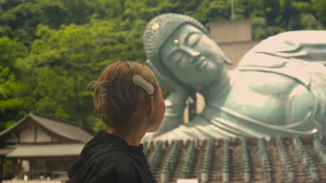 beautiful latin tourist enjoy view of giant bronze buddha at nanzoin temple fukuoka japan reclining buddha