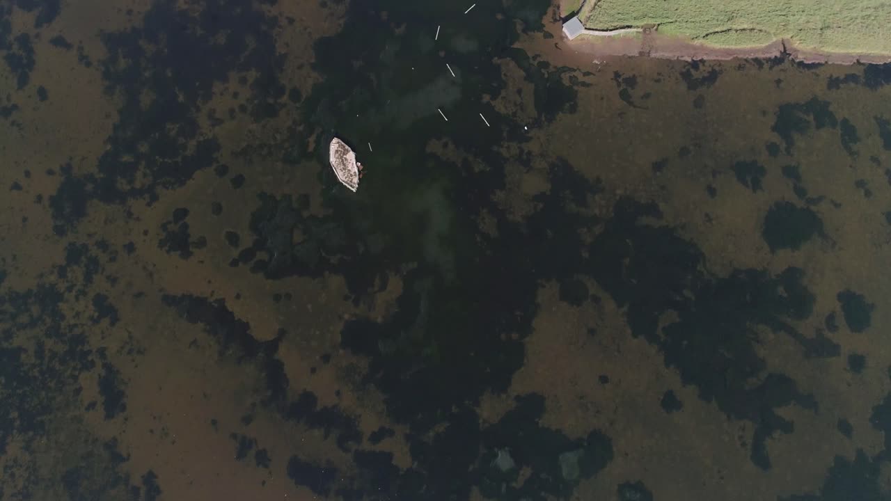 seguimiento aéreo de arriba hacia abajo sobre una península de tierra que sobresale en una laguna que apunta al sur