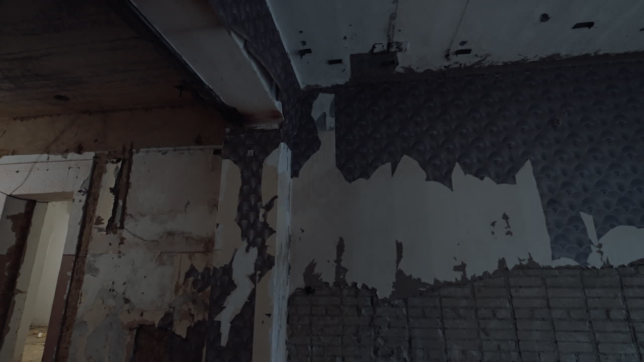 Old walls with some pieces of plaster and wallpapers on. Interior of a room being repaired, demolished or reconstructed.