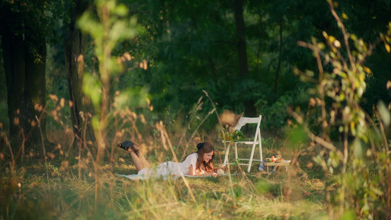 Girl lying on grass writing thoughts at picnic