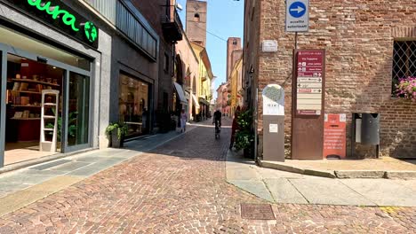 cyclist rides through a narrow italian alley