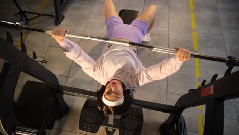 woman bench pressing in gym