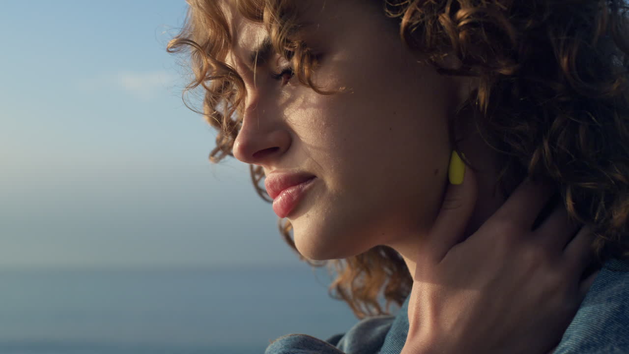 mujer molesta posando en la orilla del mar. chica pensativa tocando el cuello con la mano