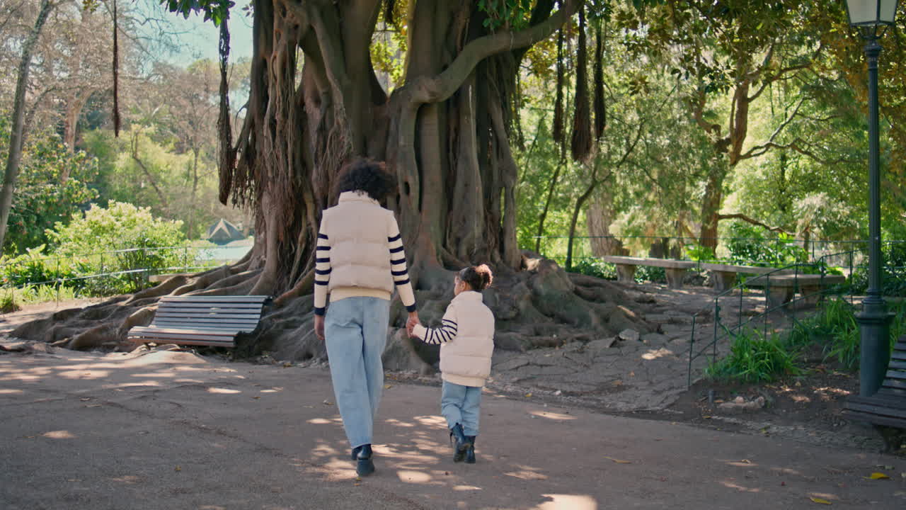 아름다운 공원에서 산책하는 편안한 여자 딸. 뒷면 행복한 가족