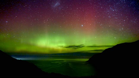 dramatic timelapse shot of aurora australis activity, capturing atoms emit visible light of distinct wavelengths and create green, red and purple colours display on the sky at nugget point new zealand