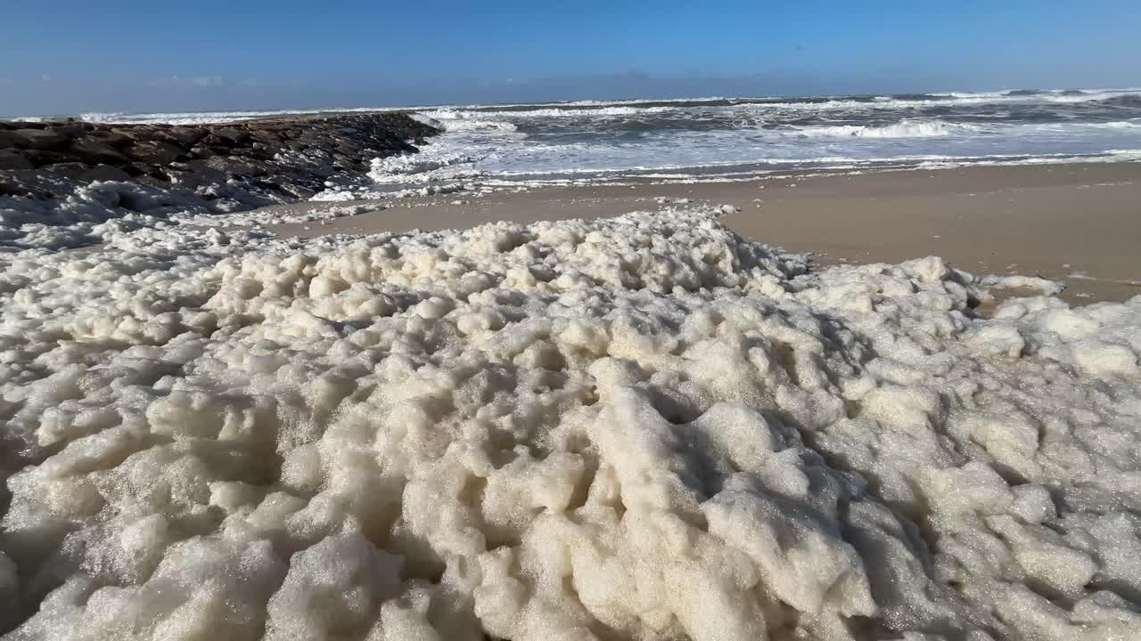 Skum fra havet hober sig op på stranden efter stormbølgerne