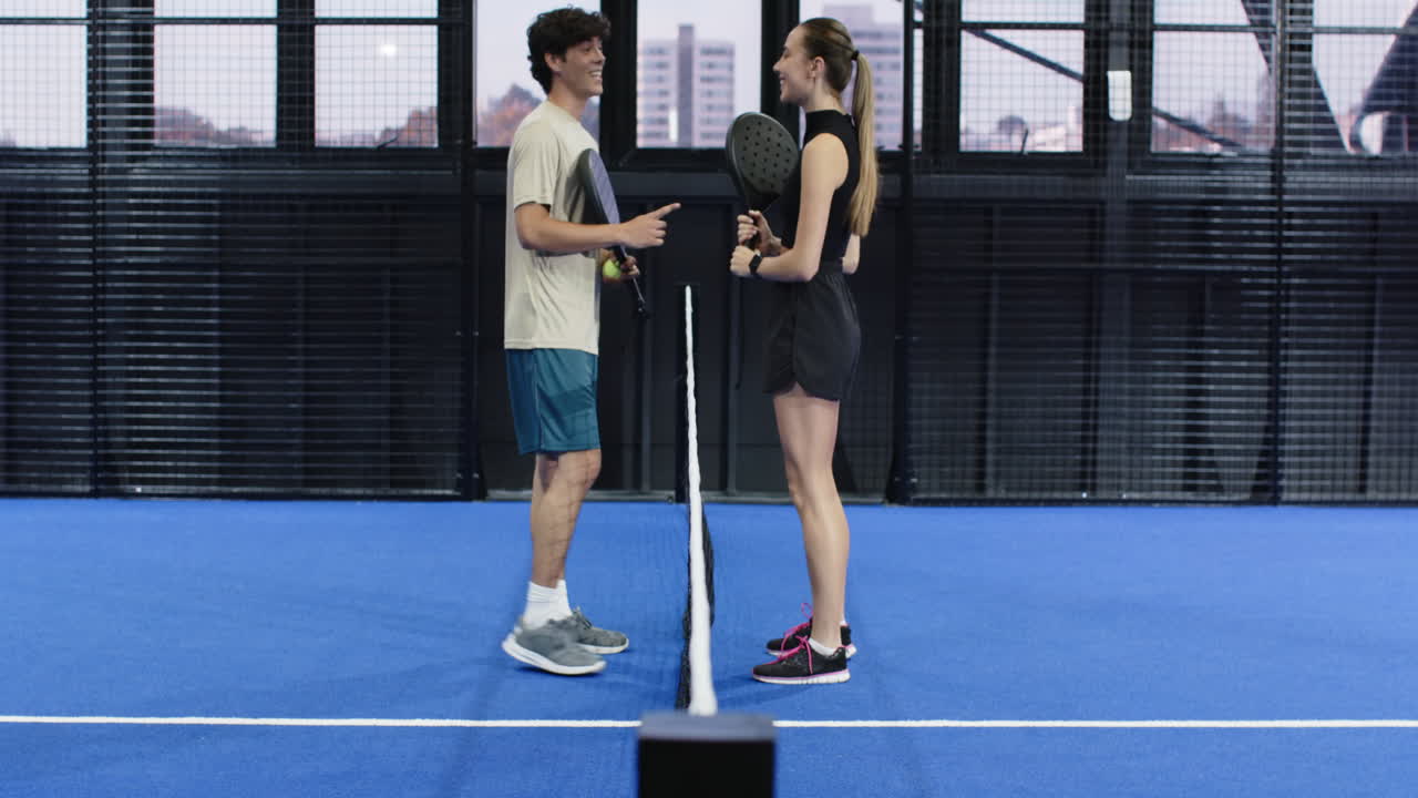 Young athletes holding rackets, facing each other on padel court, ready to play