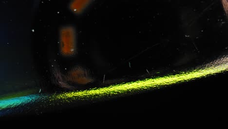 Intense-closeup-of-the-handle-of-a-stapler-panning-right-to-left-illuminated-by-metallic-blue-and-green-lights-with-black-background