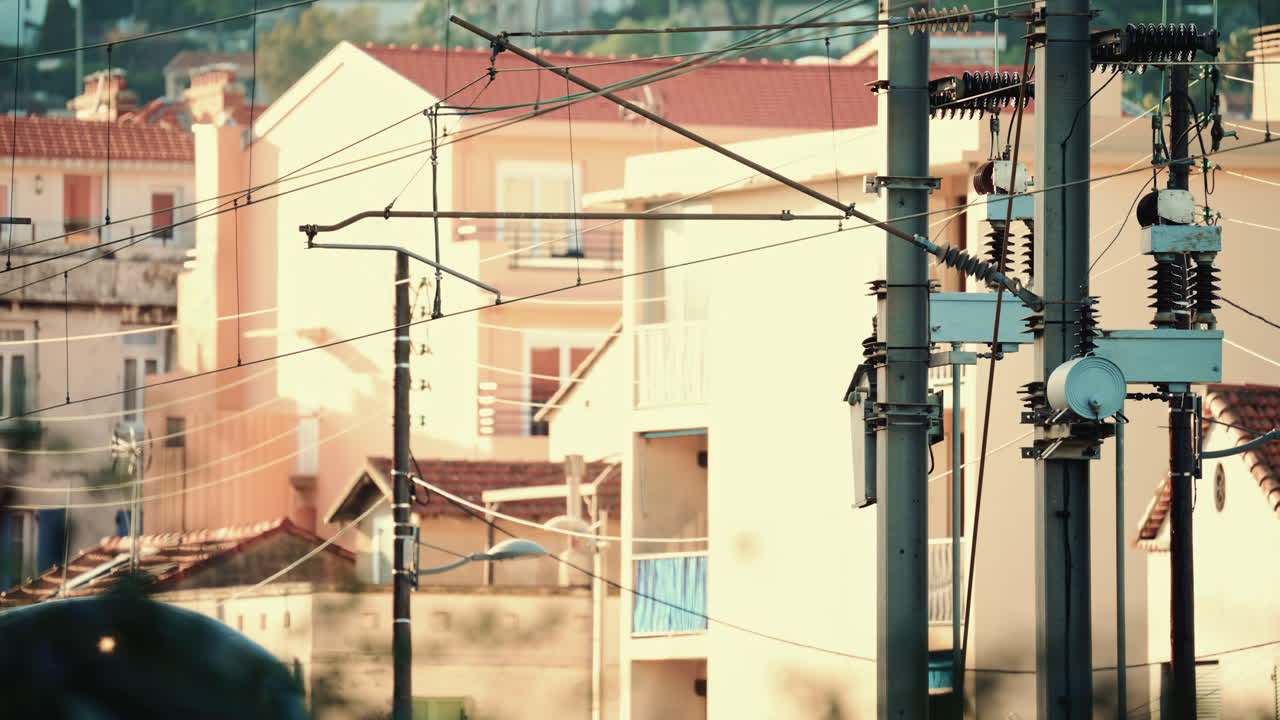 Close up of an electric train passing beneath overhead power lines and utility structures