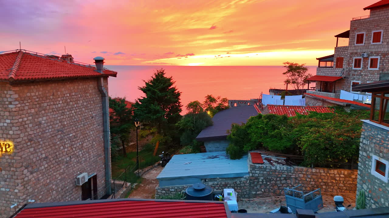 Ulcinj, Montenegro, 14 August 2025: Sunset over stone village. Fiery coastal sunset lighting stone houses in Montenegro