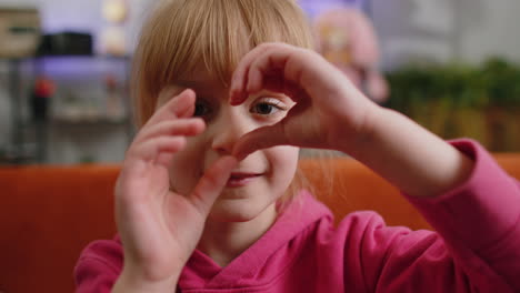 niña joven niña hace símbolo de amor, mostrando el signo del corazón a la cámara, expresar sentimientos románticos