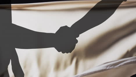 animation of silhouettes of people shaking hands and floating cloth on black background