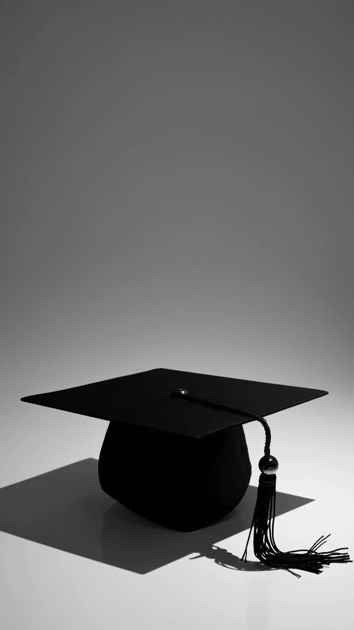 A minimalist video concept featuring a graduation cap on a gray background