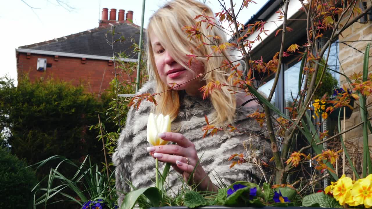 привлекательная женщина наслаждается наслаждается запахом цветов в саду средний зум в кадре медленный портрет