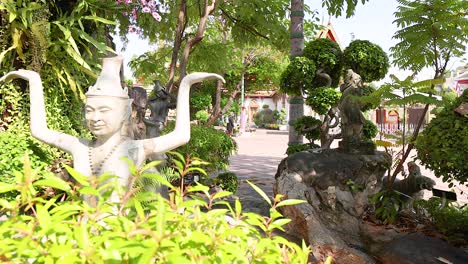 a tranquil garden scene at wat pho, bangkok, featuring intricate statues amidst lush greenery, captured in bright daylight