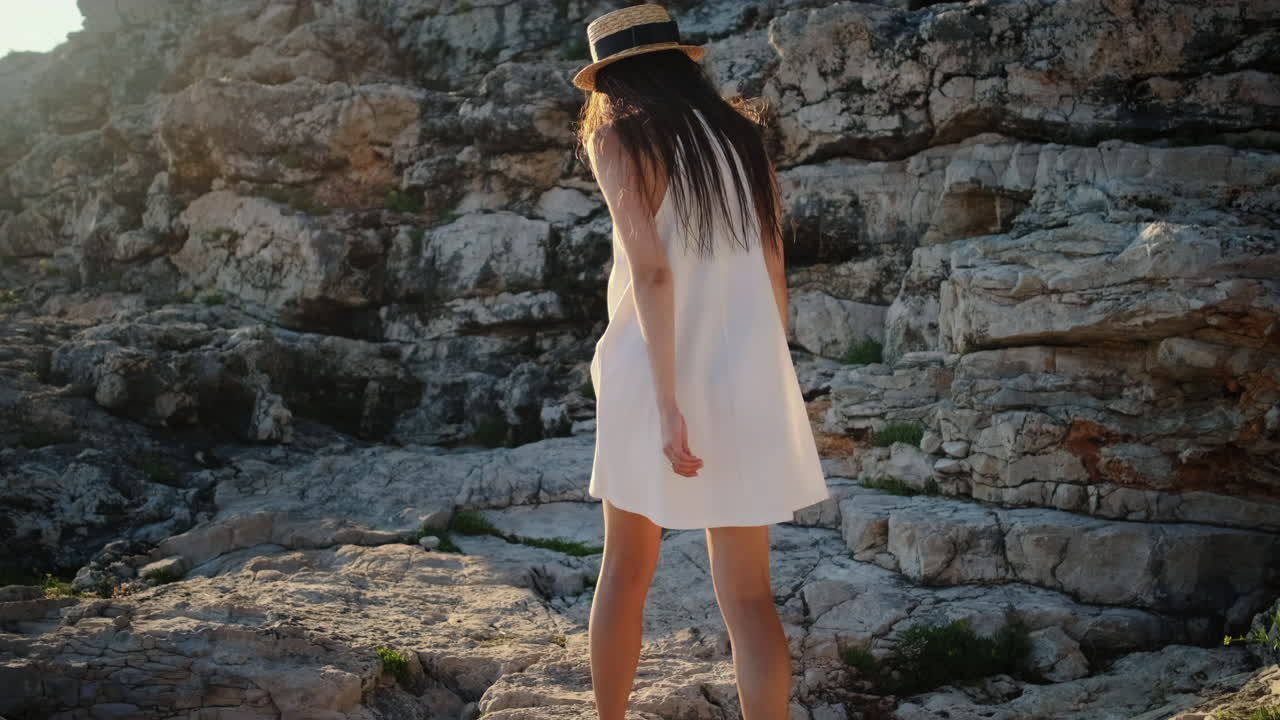 una mujer con un vestido blanco junto a las rocas.