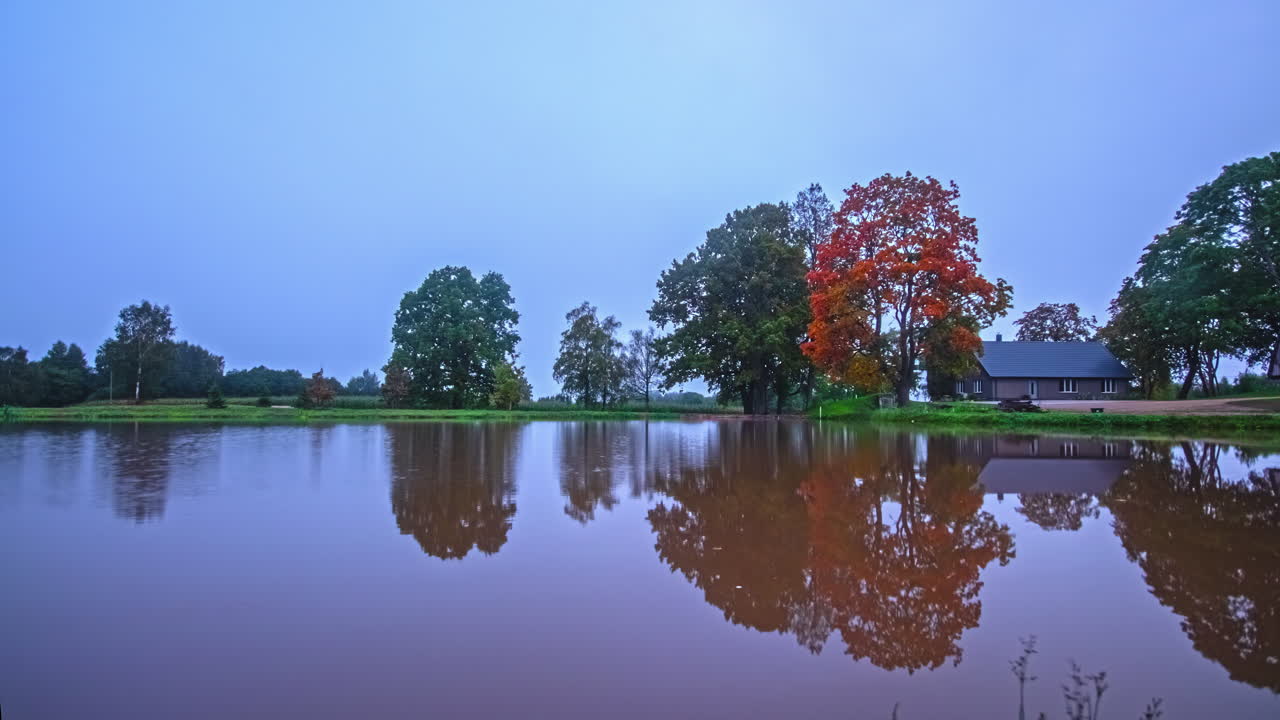 이른 아침에서 낮까지 호수와 가벼운 강우량이 있는 목조 주택의 융합 시간 경과