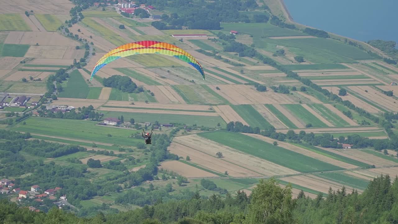 A breathtaking flight as a paraglider glides just above the trees, then rises higher over a stunning landscape.