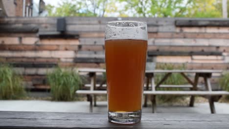 A-tall-glass-of-fresh-beer-on-a-picnic-table-in-a-backyard-on-a-nice-summer-sunny-day