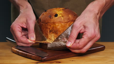 Traditional English Christmas cake tied with a jute thread on the black background. Italian classic Panettone .Pastry Chef sprinkles powdered sugar through a sieve on the fruit Easter cake with raisins. High quality 4k footage