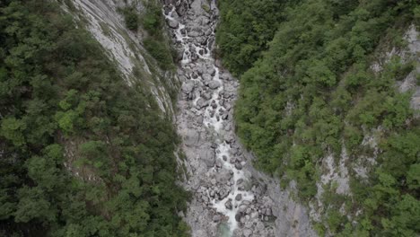 Video-of-a-flat-drone-view-of-a-descriptive-frontal-bird-over-the-river-of-the-Boka-cascasa-and-the-cascaca-on-the-horizon-in-Slovenia